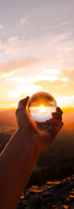 Main tendue tenant une boule de cristal, symbole de clairvoyance et de guidance spirituelle dans les consultations de médium